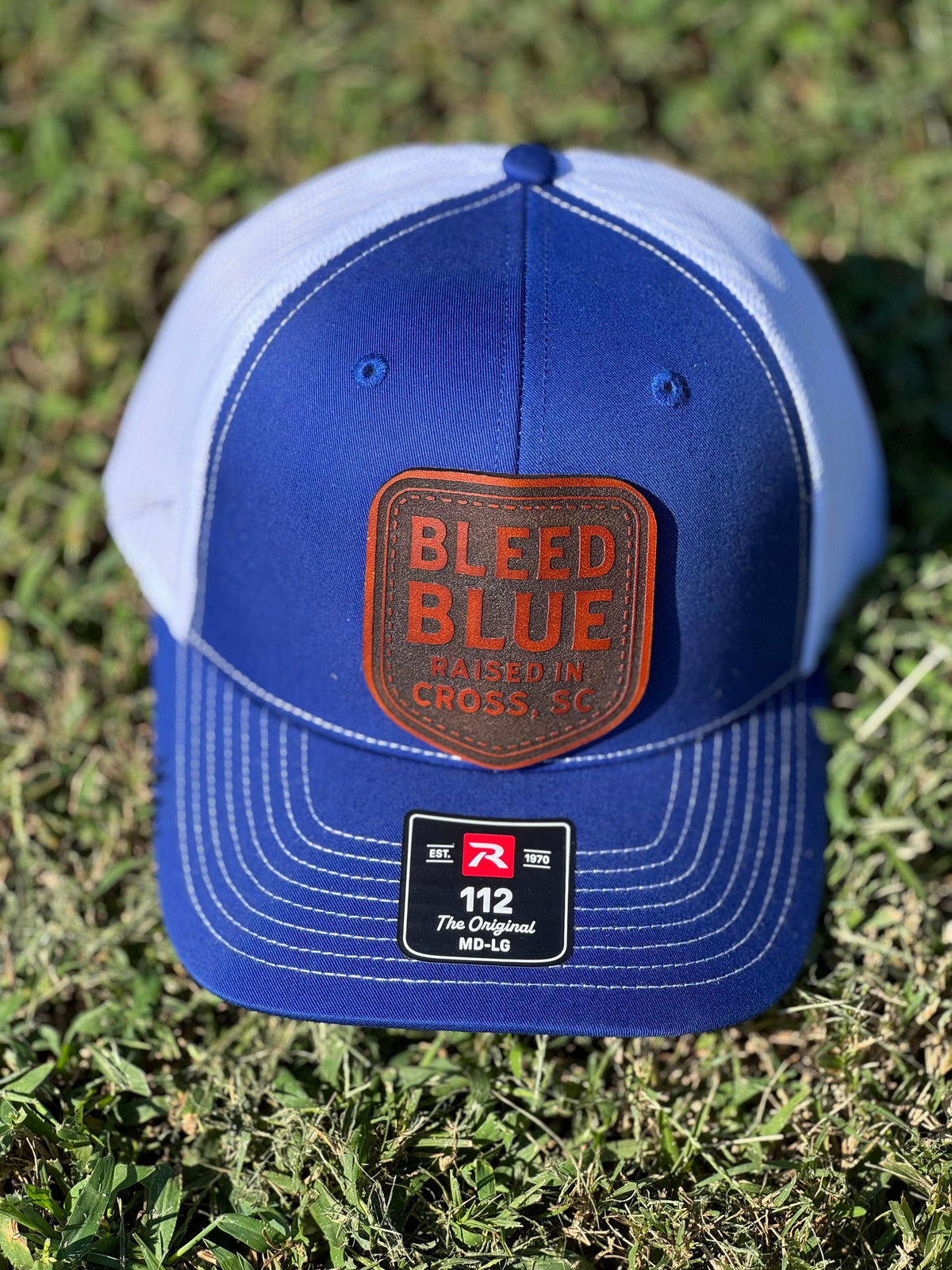 Royal blue and white hat with a leather patch reading Bleed Blue.