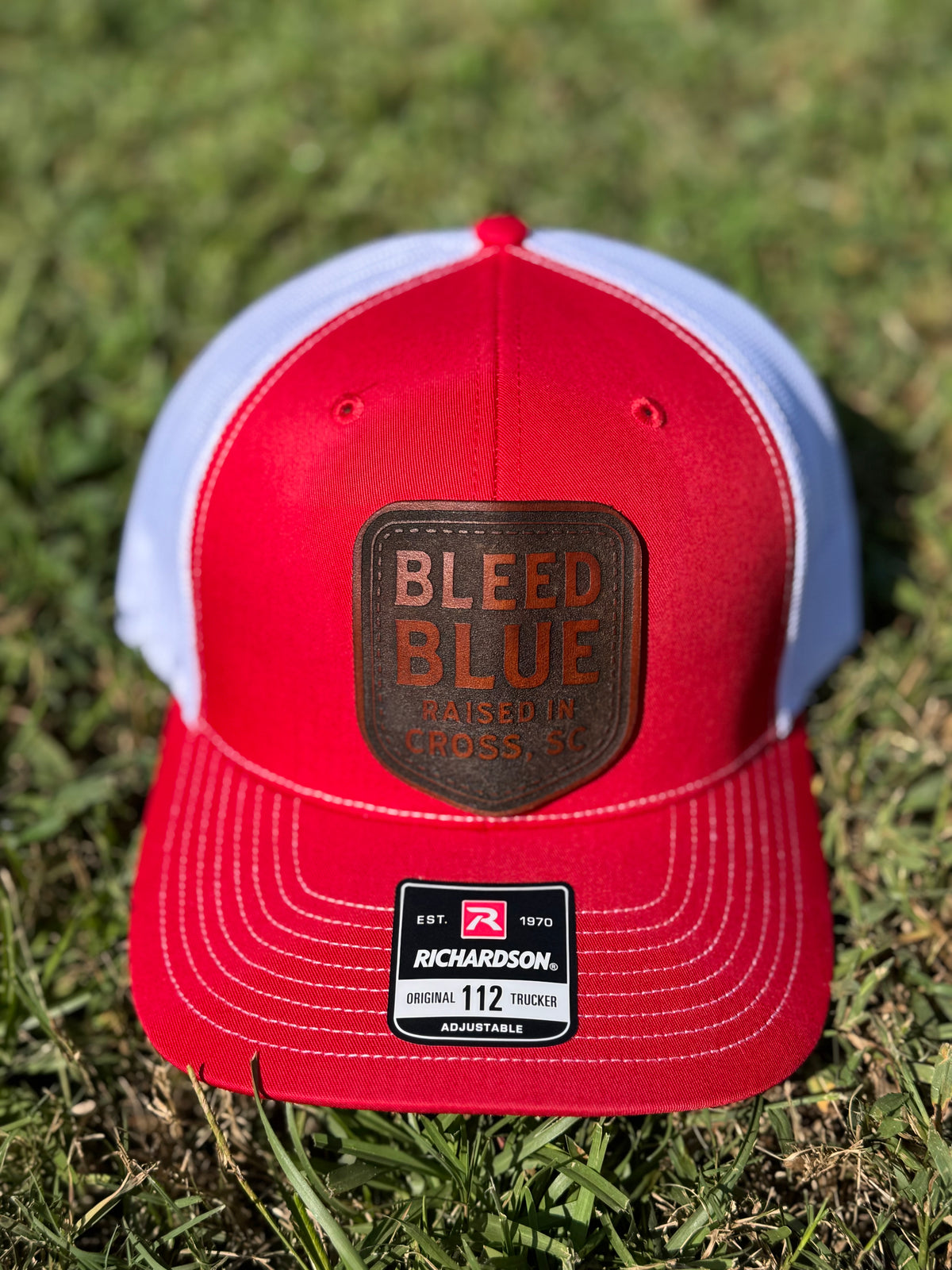 Red and white Richardson 112 trucker hat with a Bleed Blue leather patch.